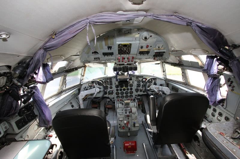 Original cockpit: two yokes, analog gauges, two seats, purple curtains, grass through the windshield