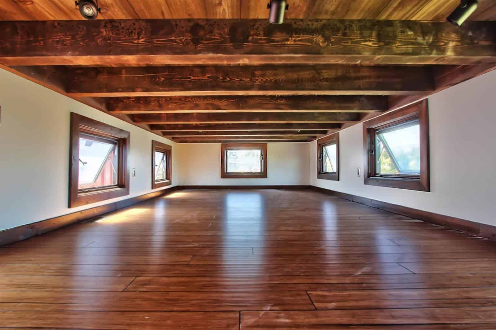 Empty great room inside the Wedge with exposed timber ceiling beams, wood floors, and angled trapezoid windows