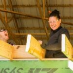 Two students laugh while framing a tiny house under an open pavilion at Wild Abundance near Asheville