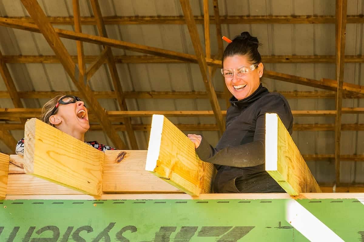 Two students laugh while framing a tiny house under an open pavilion at Wild Abundance near Asheville