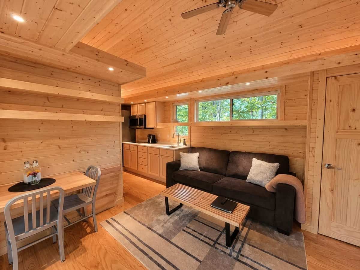 Open living and dining area with a sofa, two-seat dinette, and the galley kitchen beyond under a clerestory window at the Woodland Lot 12