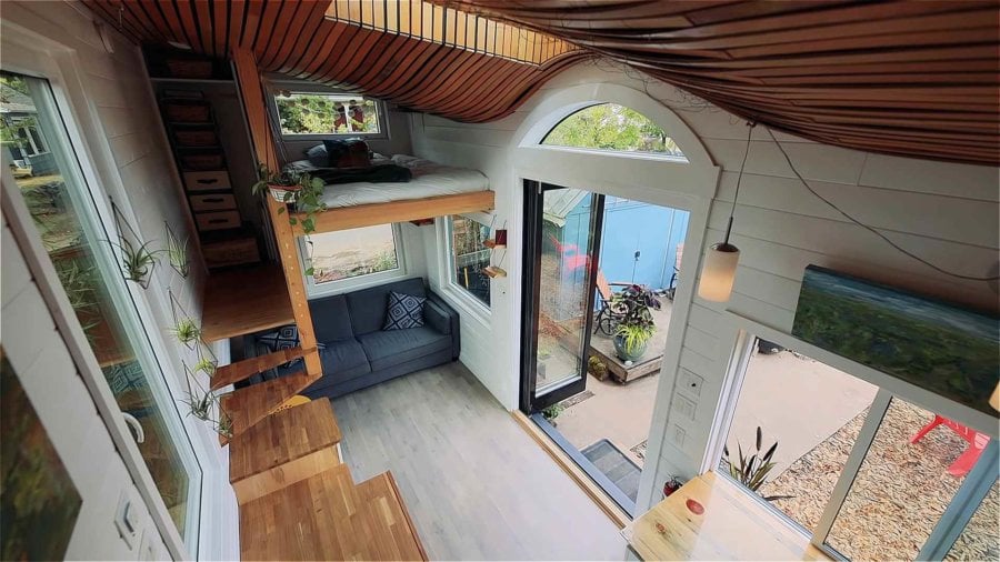 Wide view of the living room, curved ceiling and sleeping loft from the kitchen end of the tiny house