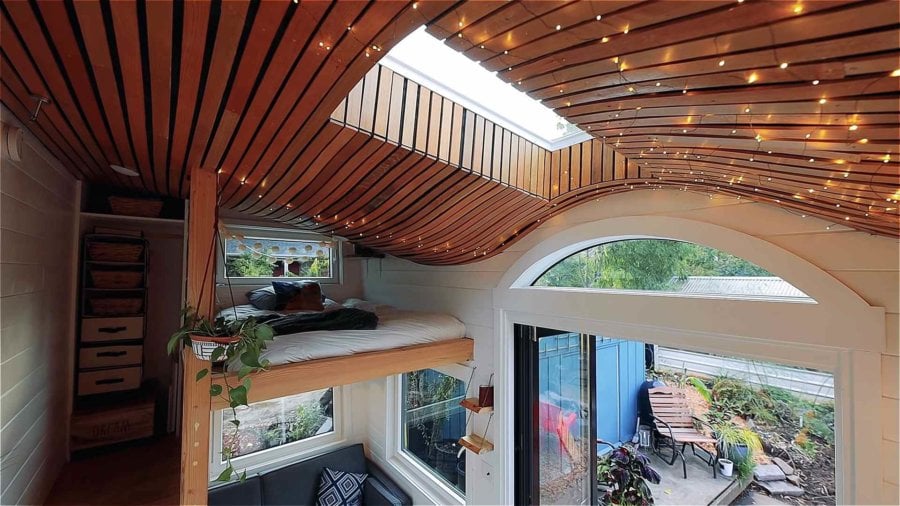 Curved reclaimed oak ceiling with string lights, skylight and arched window over the entry