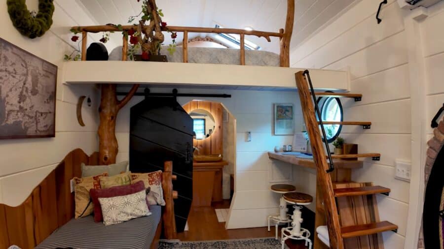 Cozy tiny house interior featuring a loft, wooden stairs, and compact living area.