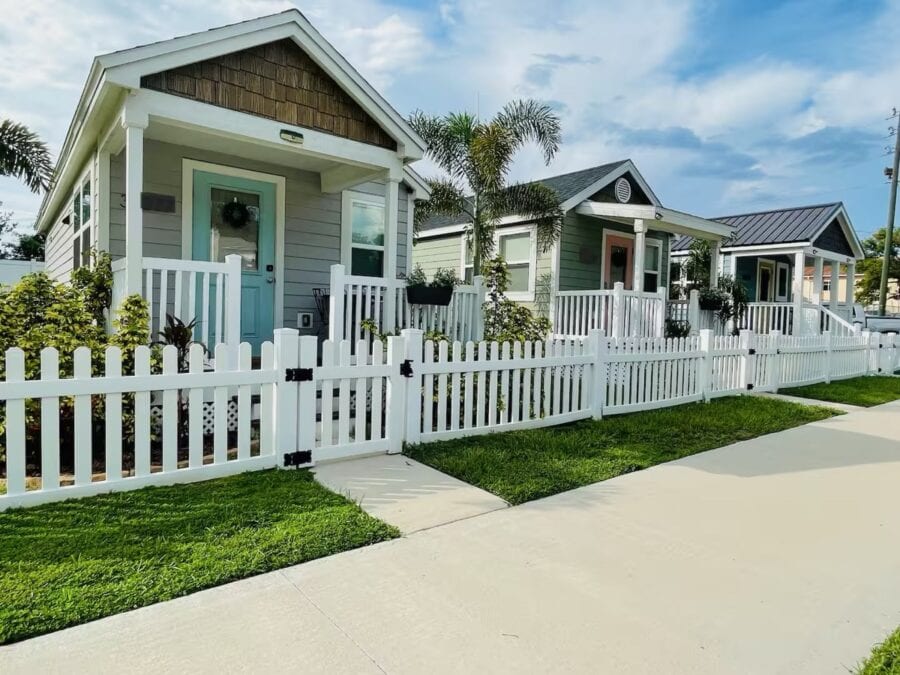 Charming tiny house with a white picket fence and lush greenery in Florida.