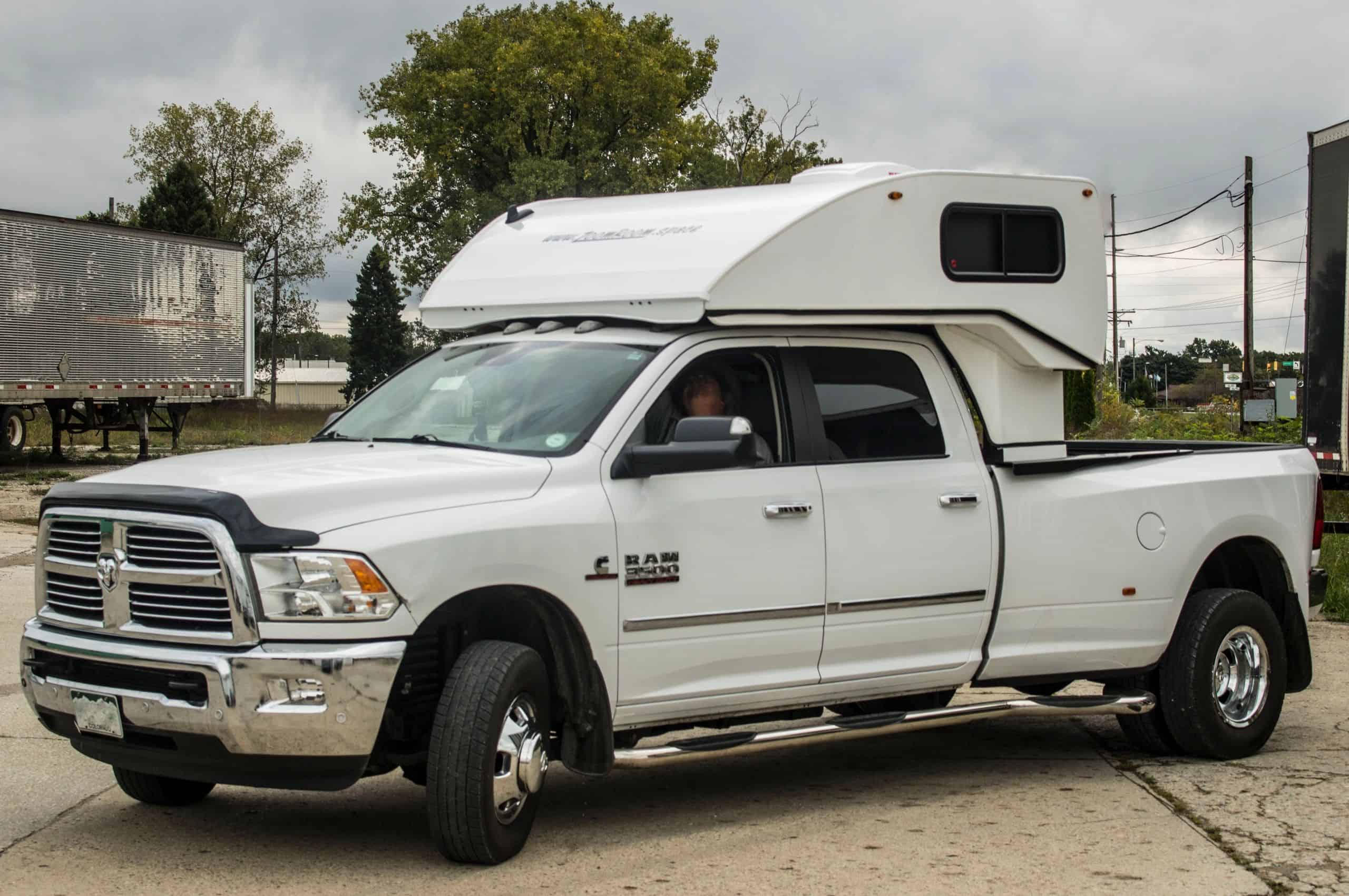 White pickup with a white ZoomRoom over-the-cab sleeper lowered — official ZoomRoom / Inoventure Industries photo